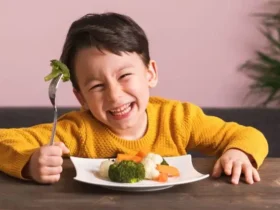 Anak tertawa bahagia sambil makan makanan bergizi untuk anak di rumah